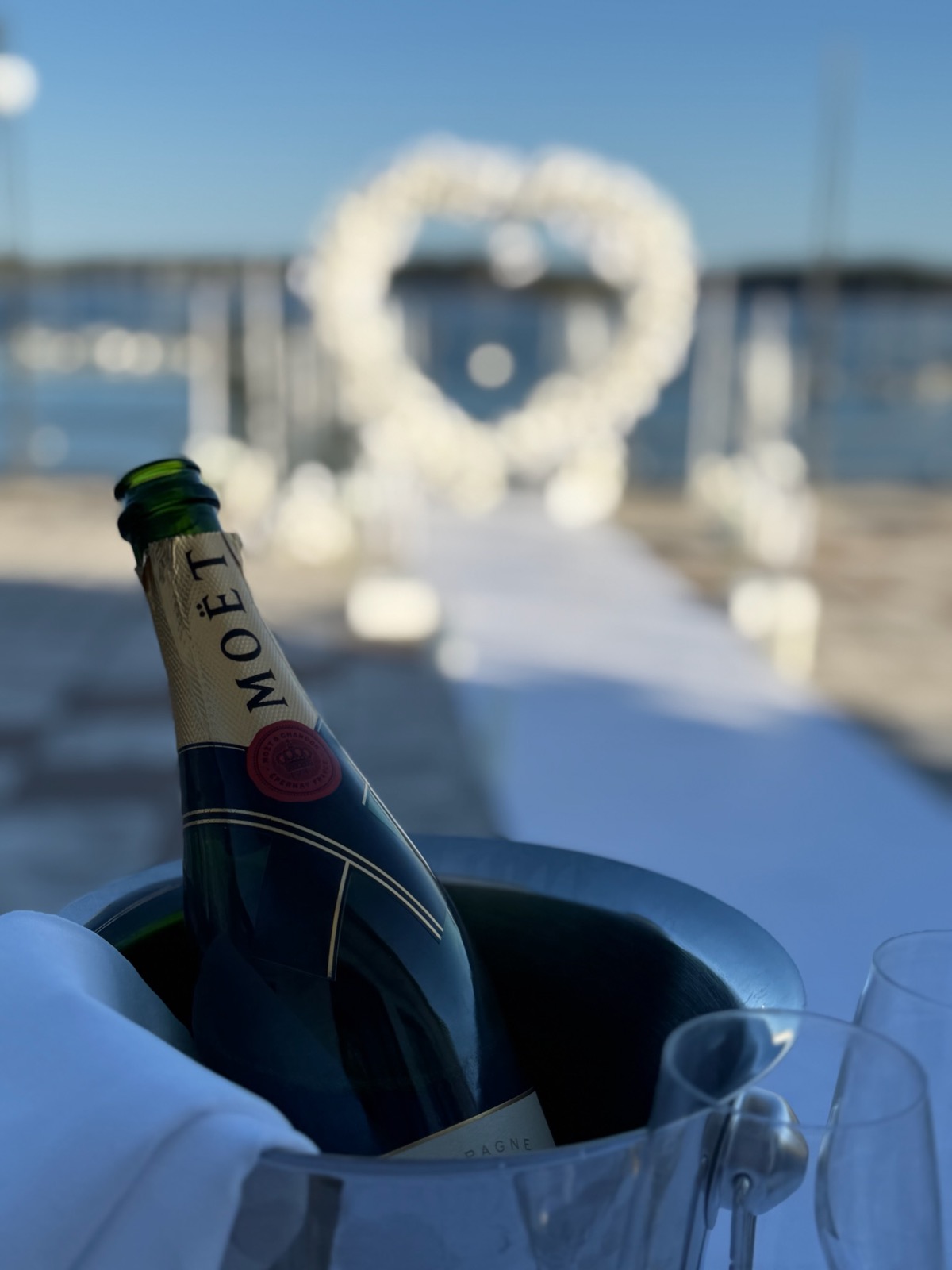 Moët champagne med blomsterhjärta vid vattnet i bakgrunden