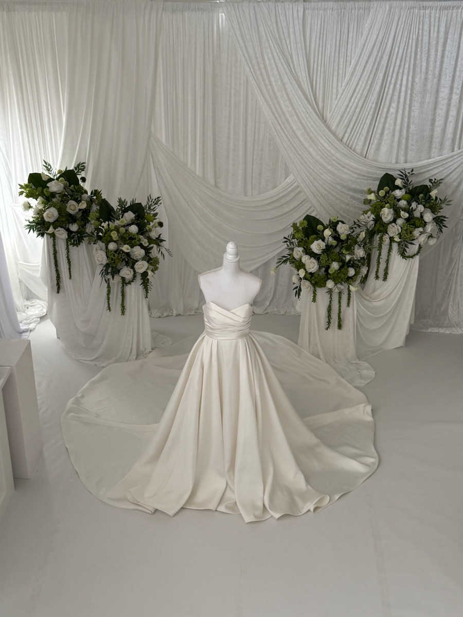 Brudklänning i champagne satin med gröna och vita blomsterarrangemang